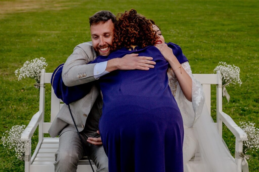 ellen-spoor-trouwambtenaar-met-paarse-toga-omhelst-bruidspaar