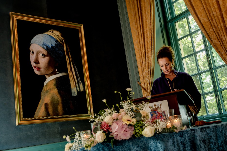 ellen-spoor-trouwambtenaar-spreekt-speech-uit-achter-spreekmeubel-met-bloemen
